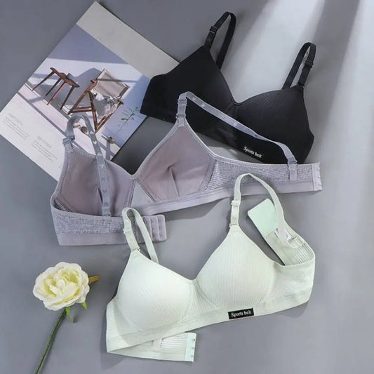 Three bras in black, gray, and white on a gray surface with a flower and magazine.