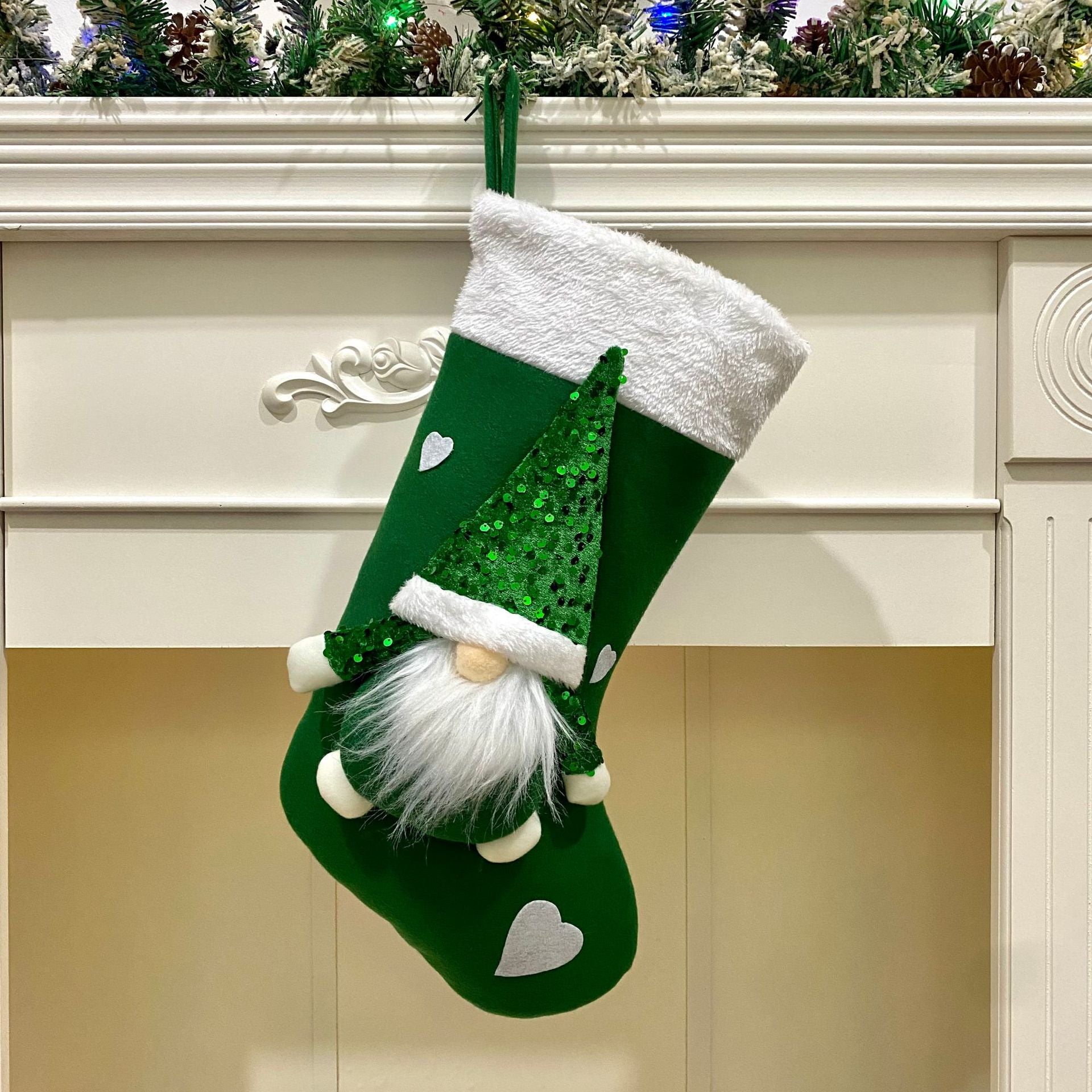 Green Christmas stocking with a gnome design hanging on a fireplace mantle.
