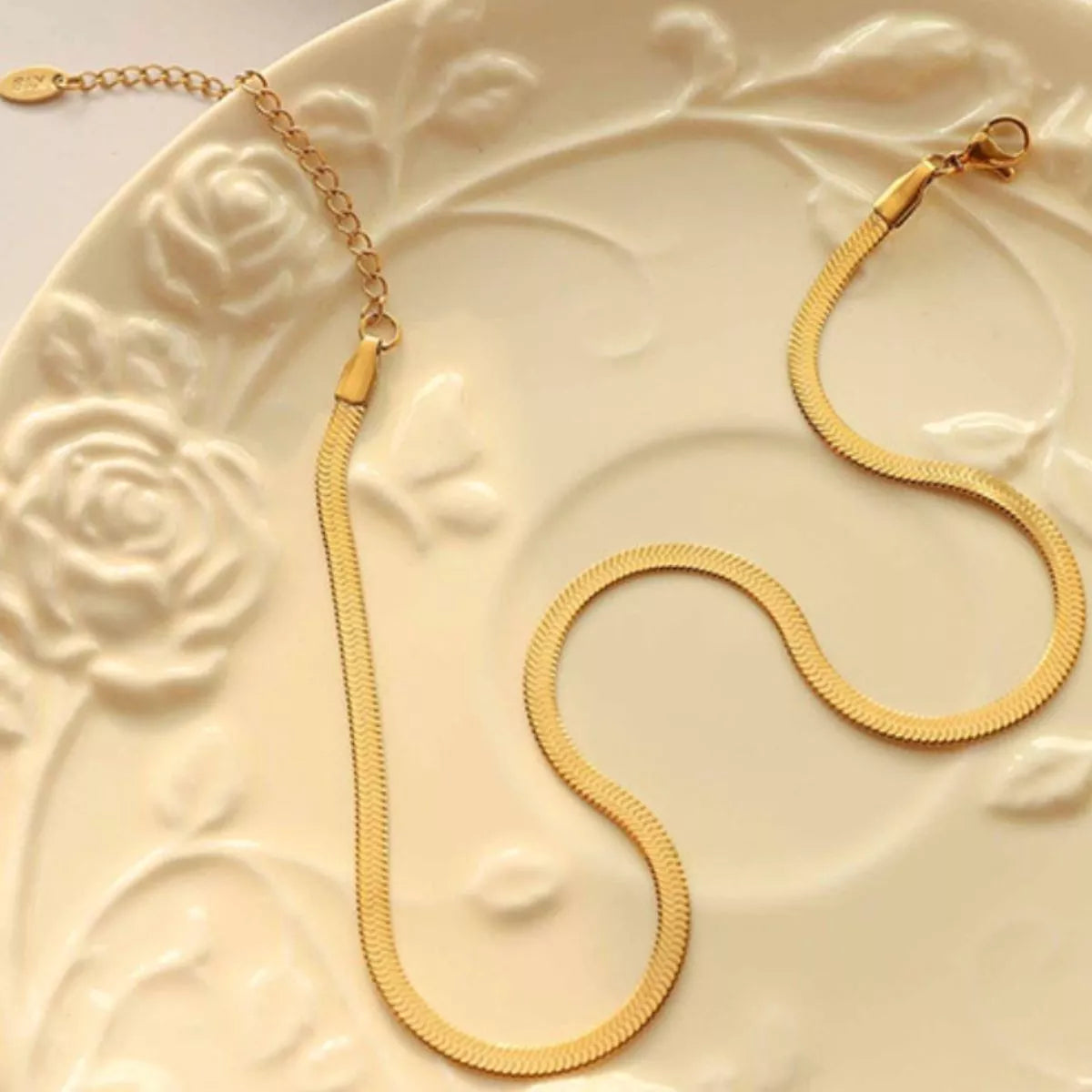 Gold necklace on a decorative white plate with floral patterns