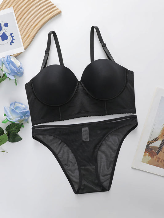 Black bra and panties set on a light surface with decorative elements.