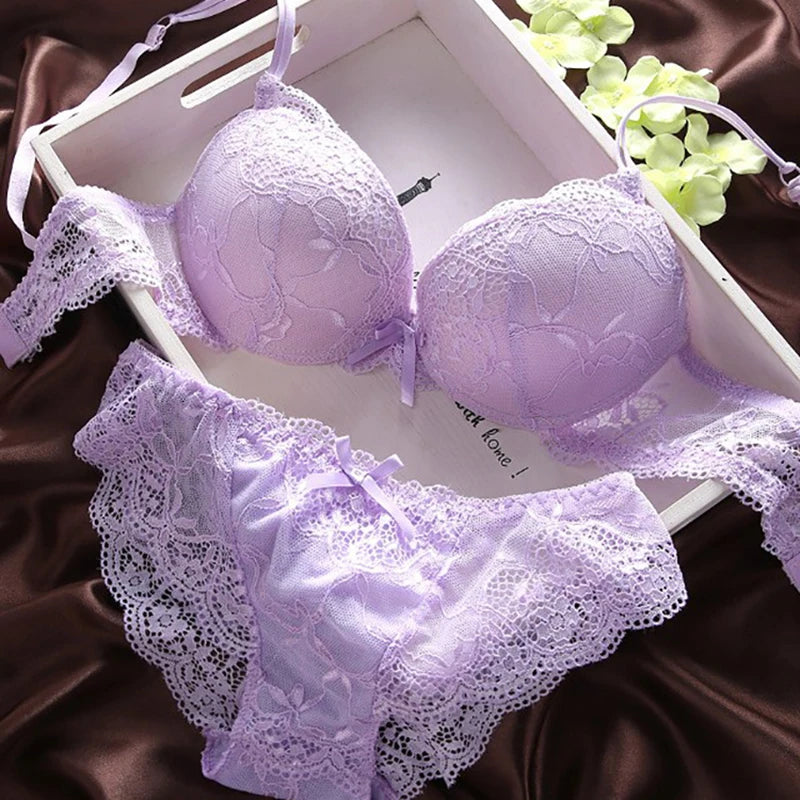 Lavender lace bra and panties set on a white tray with green flowers.