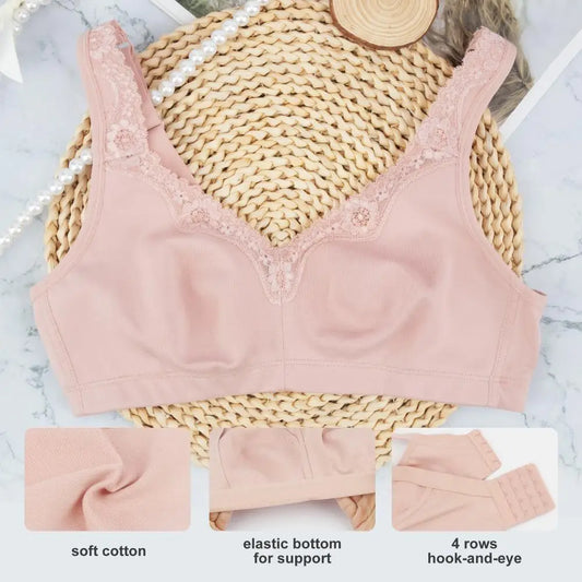 Pink bra with lace details on a woven mat, surrounded by pearls and a straw hat.