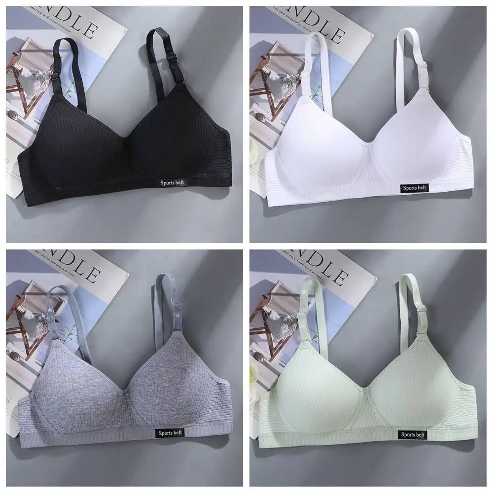 Four different colored bras displayed on a gray surface with a magazine underneath.
