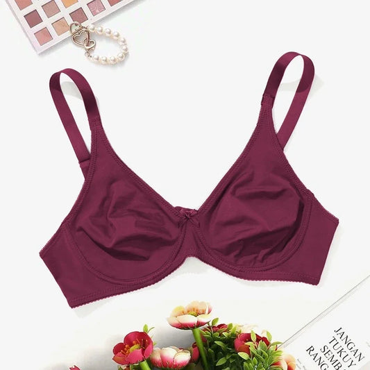 Maroon bra on a white background with flowers and makeup palette.