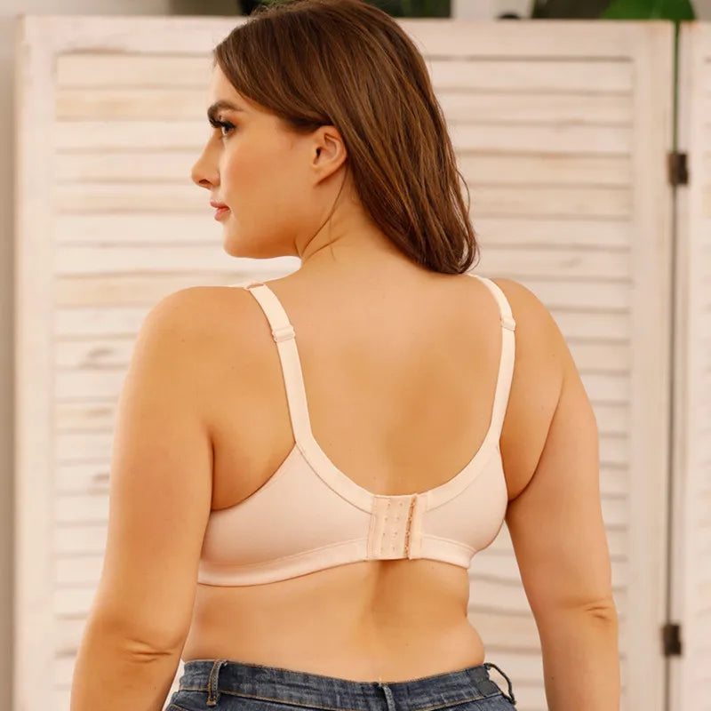 Woman wearing a beige bralette with a neutral background